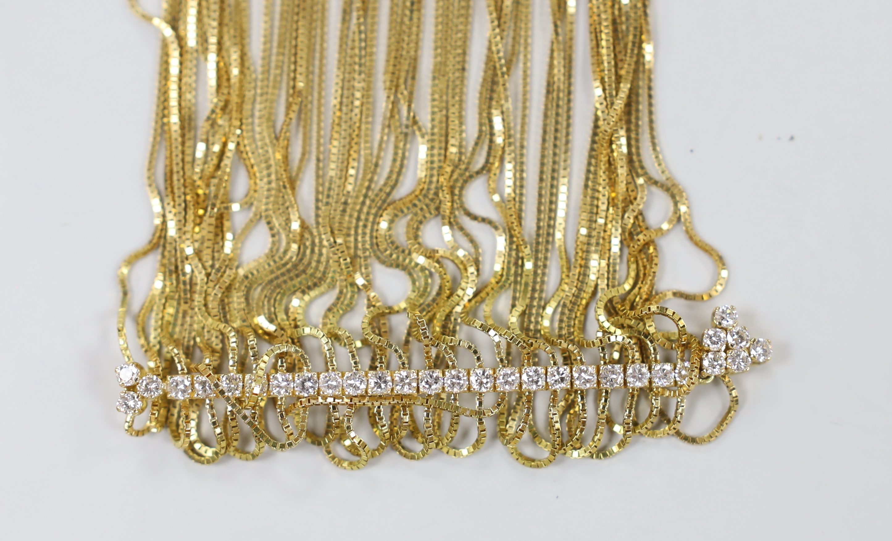 A yellow metal multi strand necklace, with thirty stone diamond set central line motif, 50cm, gross weight 74.4 grams.